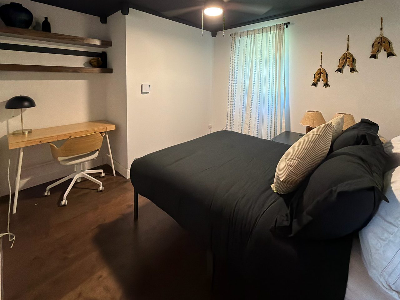 Queen bed in the moody Angler's Den with a writing desk and fish-decoy wall art, a Catskills cabin bedroom in Livingston Manor, NY