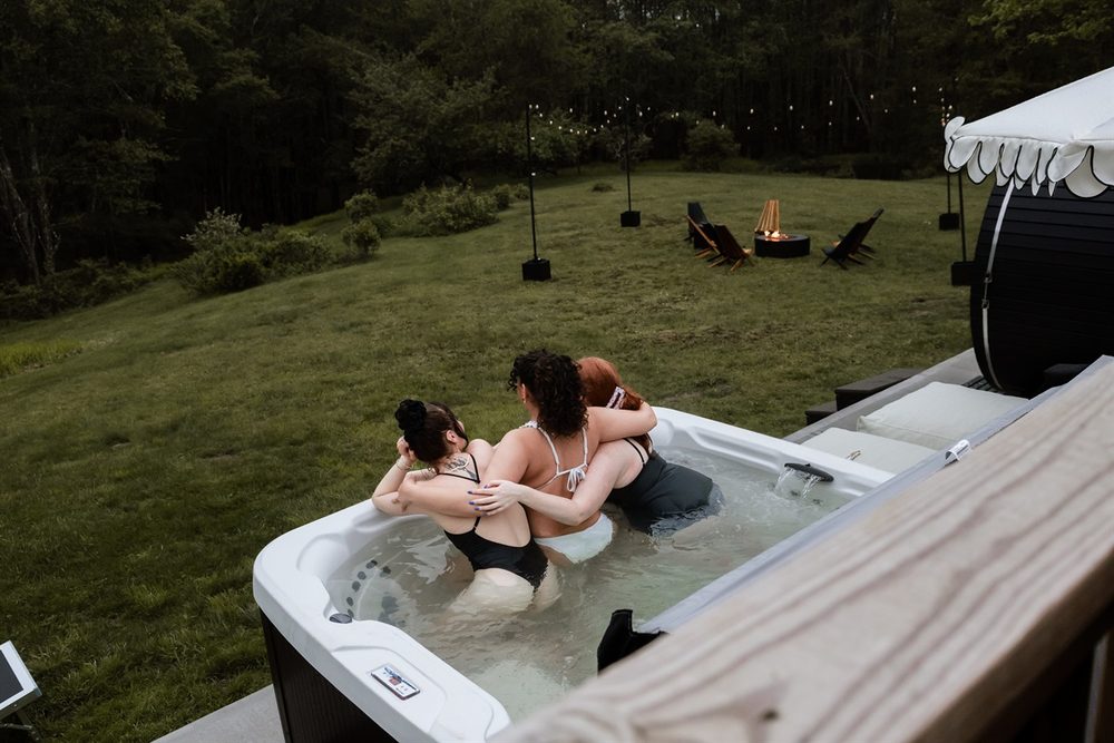 Private hot tub steaming at dusk under the trees beside the cabin deck