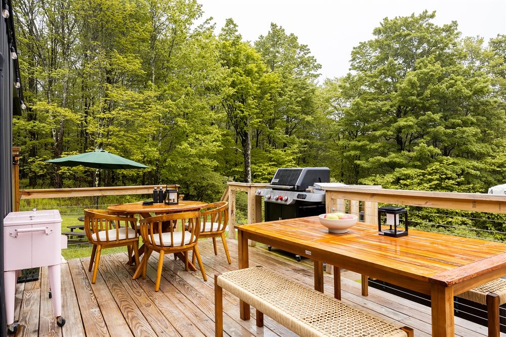 Outdoor dining table on the deck with the grill and forest views