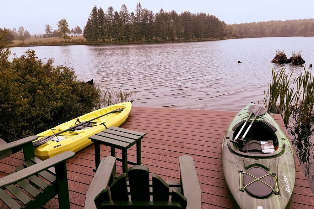 Yellow and green kayaks with paddles and life jackets tied up at the private dock