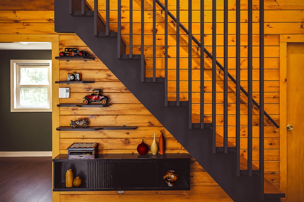 Wood staircase with black metal railings and floating shelves of vintage decor