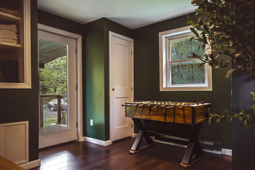 Game room with a foosball table, forest-green walls and a door to the outdoors
