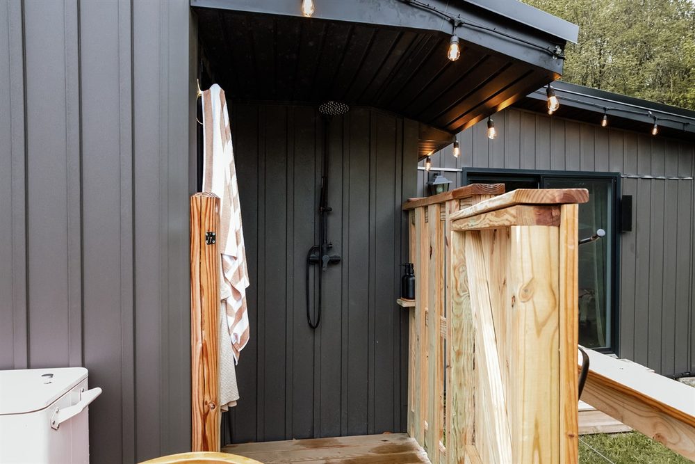 Private outdoor shower mounted on a natural wood wall among the trees