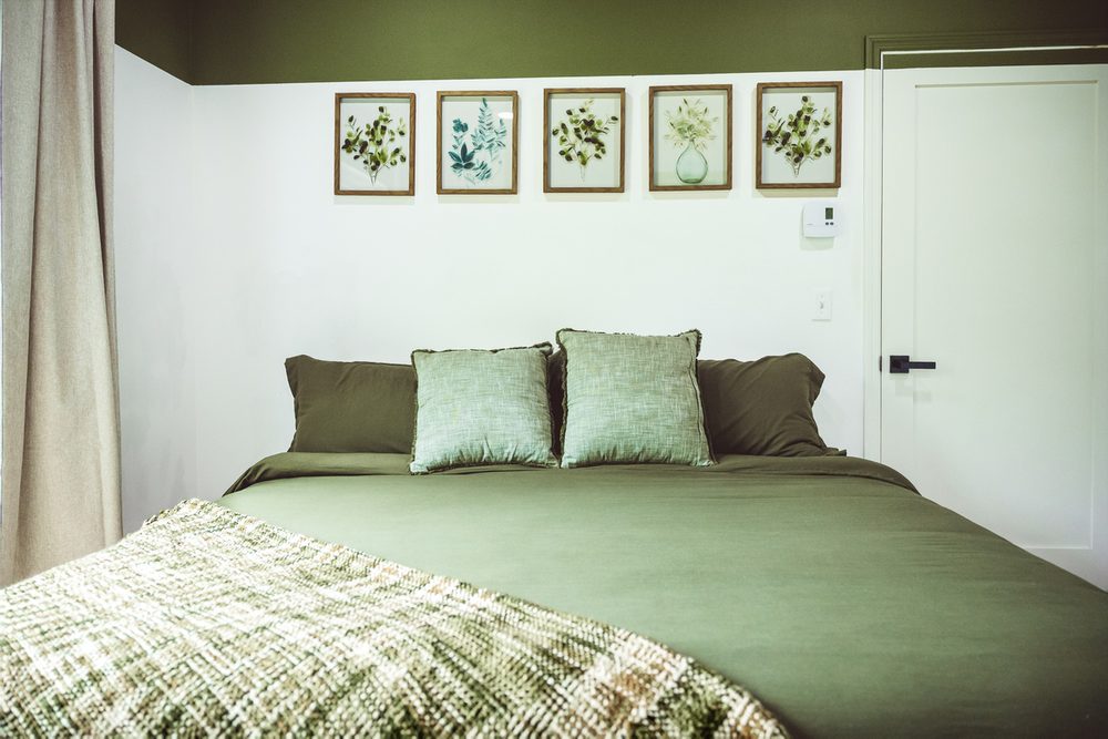 Forest-green bedding and botanical wall art in the Sunrise Suite