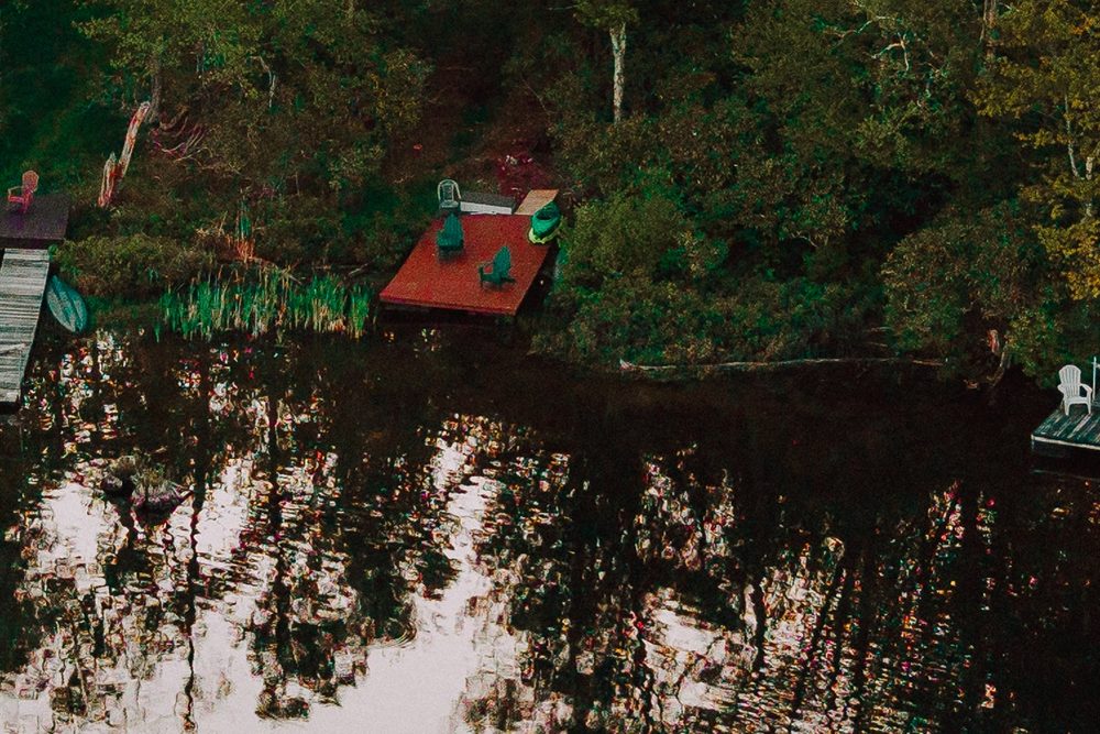 Aerial view of the private dock with Adirondack chairs, reeds and the lake's green shoreline