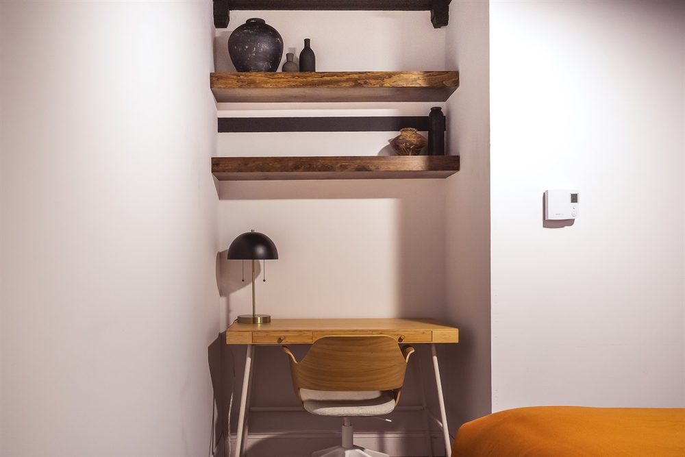Built-in wooden desk nook with a task chair, lamp and floating shelves for remote work