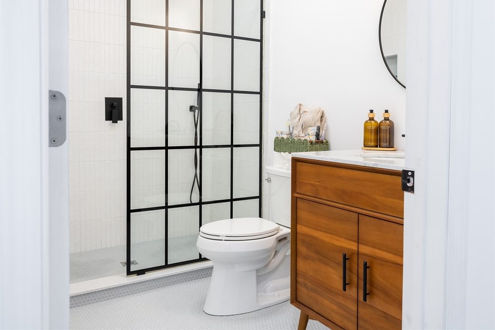 Bathroom with a black-framed glass shower and wood vanity