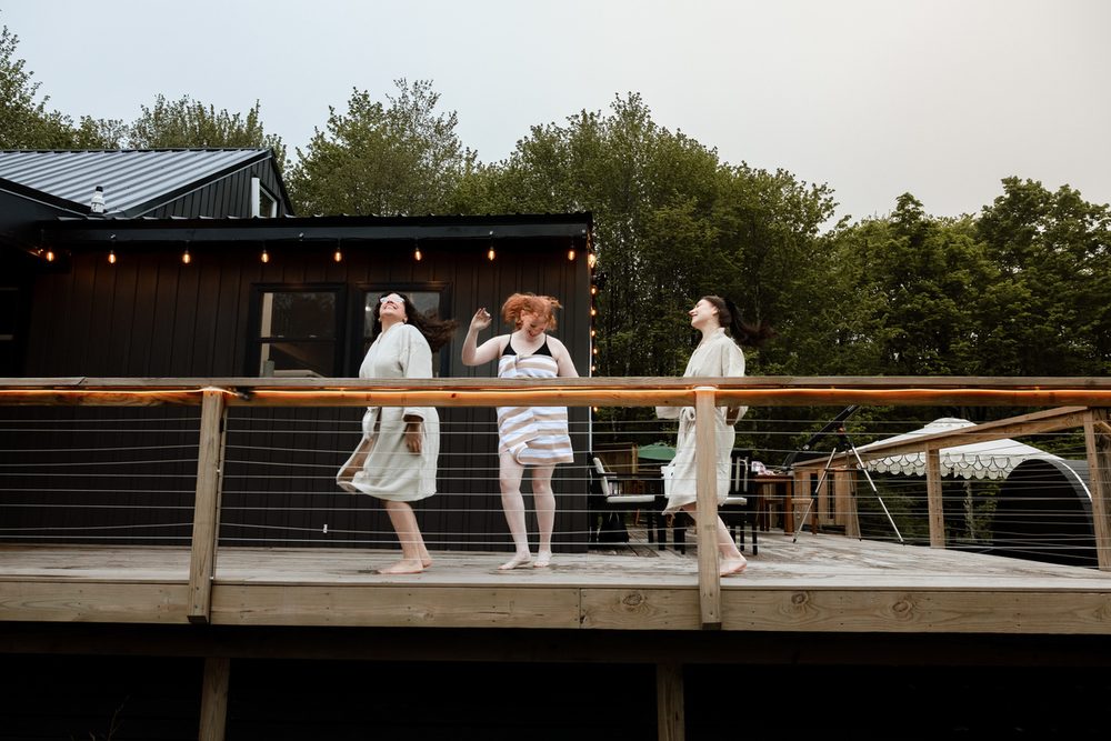 Three friends in robes on the deck, heading for the hot tub and sauna