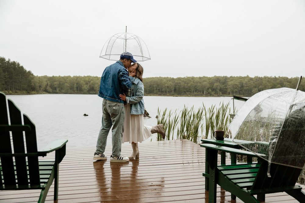 A couple under a clear umbrella on the private lake dock on a misty day