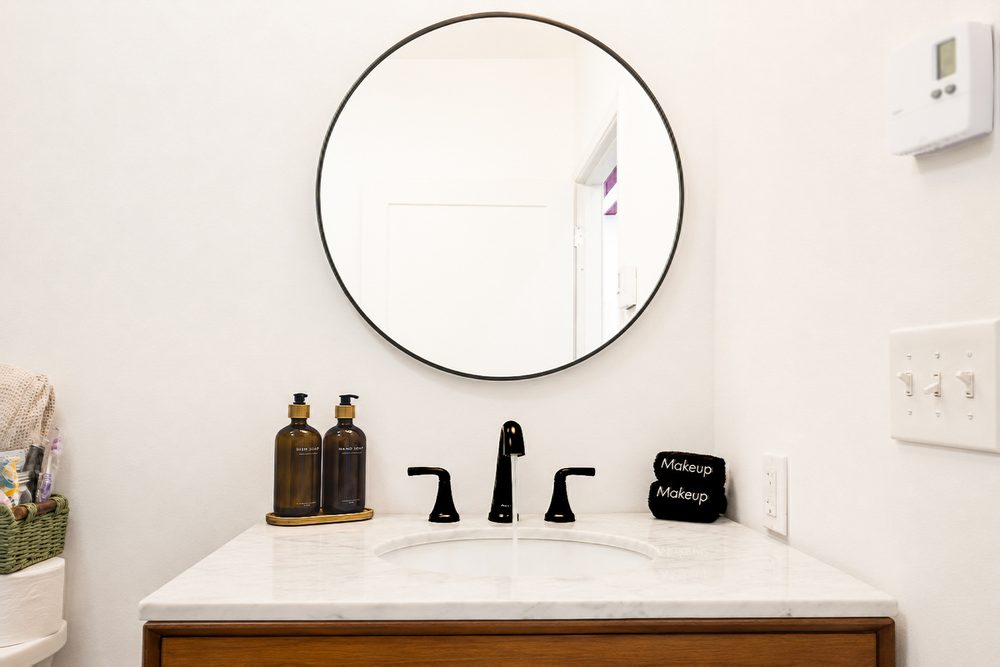 Round mirror and matte-black fixtures over a modern vanity