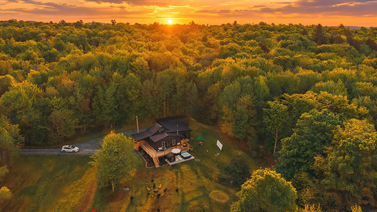 Aerial view of Inkwood Reserve at sunset, a secluded log cabin ringed by Catskills forest near Livingston Manor